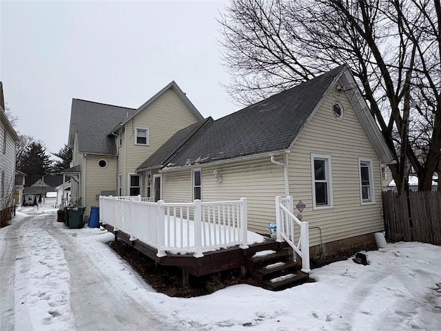 snow covered back of property featuring a deck