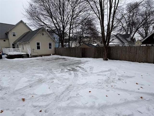 snowy yard with fence and a deck