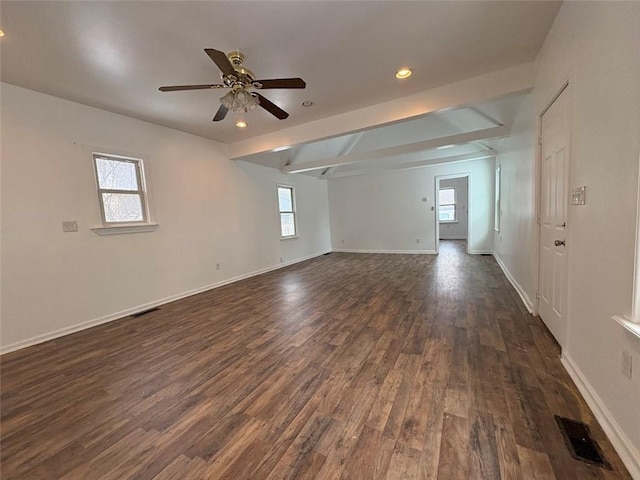 empty room with dark wood-type flooring, a ceiling fan, visible vents, and baseboards