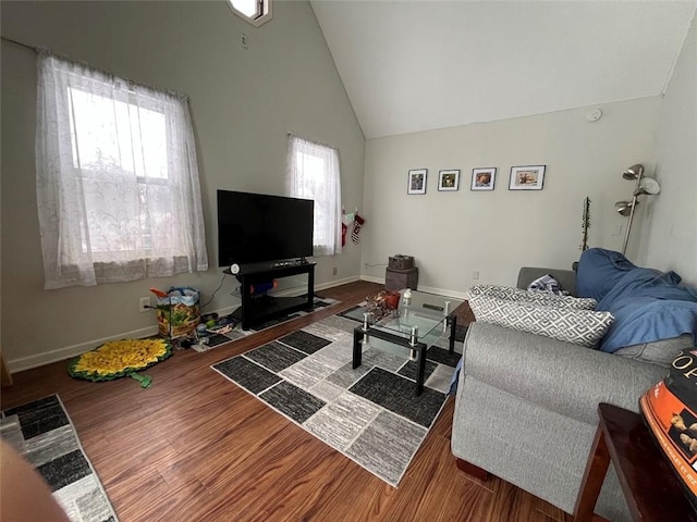 living area with high vaulted ceiling, baseboards, and wood finished floors