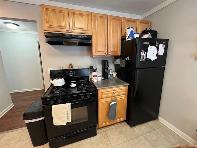 kitchen featuring baseboards, dark countertops, brown cabinets, under cabinet range hood, and black appliances