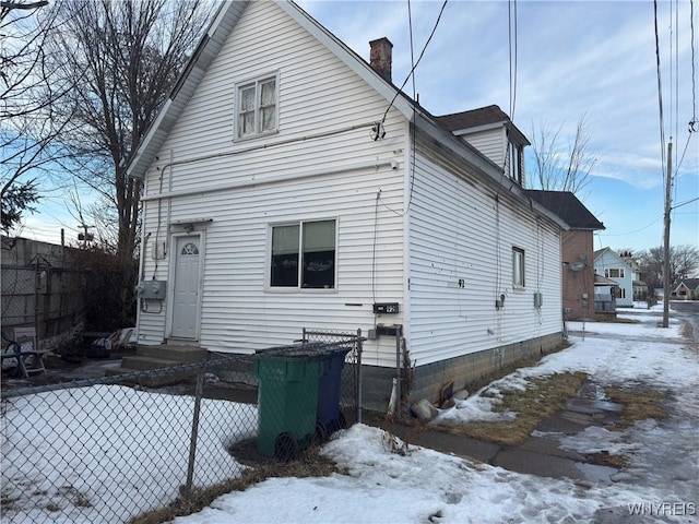 snow covered house with entry steps and fence