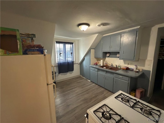 kitchen featuring white appliances, baseboards, visible vents, dark wood finished floors, and a sink