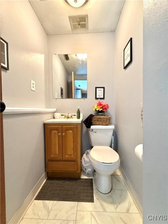 bathroom featuring marble finish floor, visible vents, toilet, vanity, and baseboards