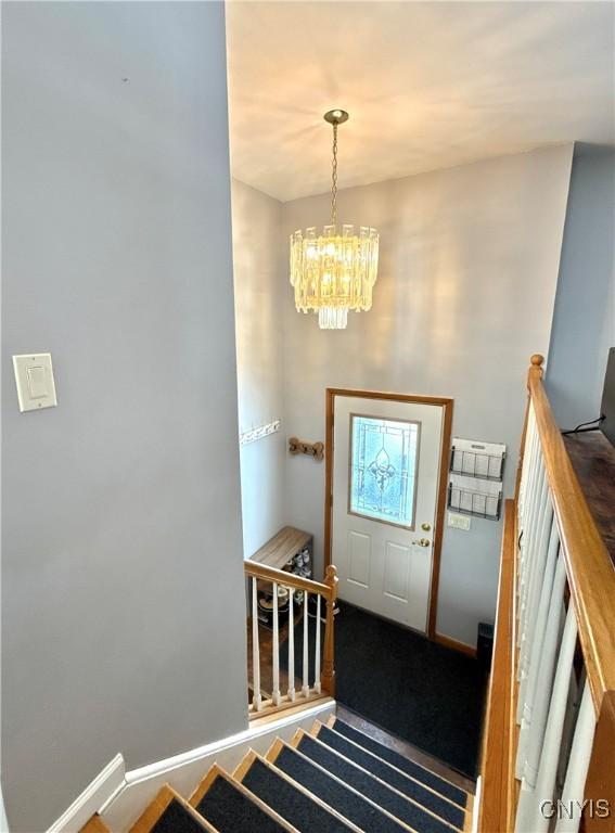 entryway featuring baseboards, stairway, and a chandelier