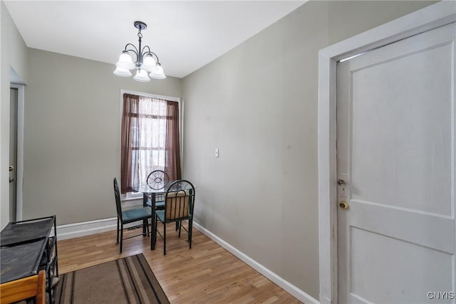 dining room with a notable chandelier, baseboards, and wood finished floors