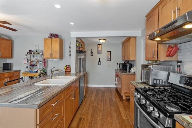 kitchen featuring under cabinet range hood, appliances with stainless steel finishes, light countertops, and a sink