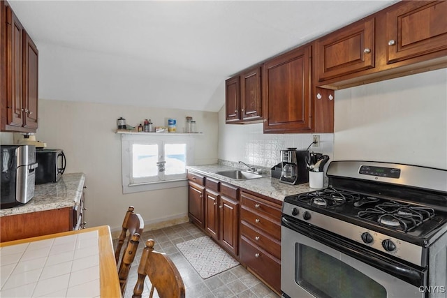 kitchen with tasteful backsplash, lofted ceiling, light countertops, a sink, and stainless steel gas range oven