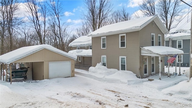 snow covered property with a garage and an outdoor structure