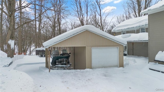 snow covered garage featuring a garage and a carport