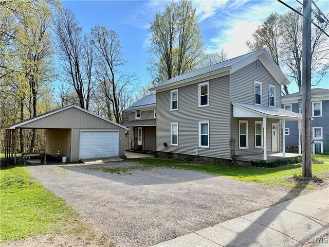 213 Salisbury St, Sandy Creek, NY 13145 - view of front facade featuring a detached garage, a front yard, an outbuilding, covered porch, and metal roof