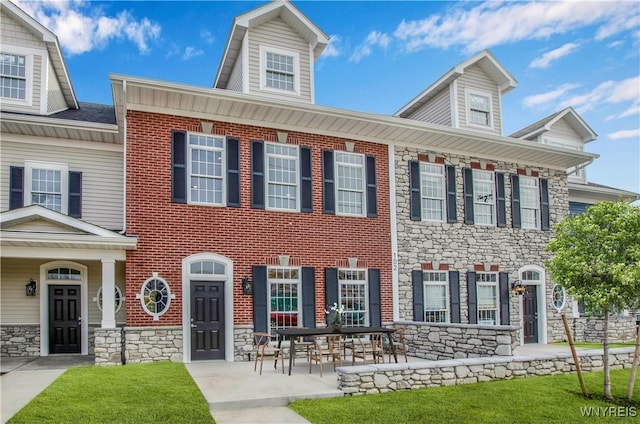 view of front of house with stone siding, brick siding, and a front lawn