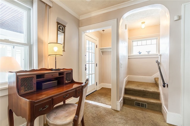 doorway with arched walkways, crown molding, light colored carpet, visible vents, and baseboards