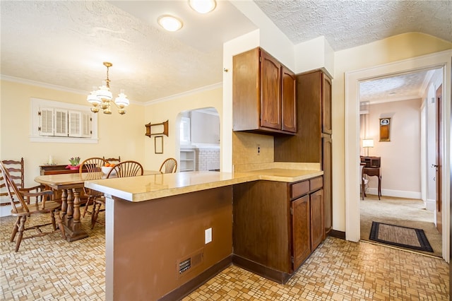 kitchen featuring light countertops, ornamental molding, a peninsula, and pendant lighting