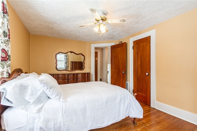 bedroom with a textured ceiling, wood finished floors, a ceiling fan, and baseboards