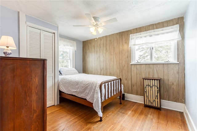 bedroom with multiple windows, baseboards, and wood finished floors