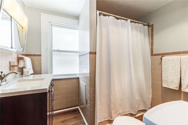 full bathroom featuring toilet, a wainscoted wall, a shower with shower curtain, vanity, and tile walls