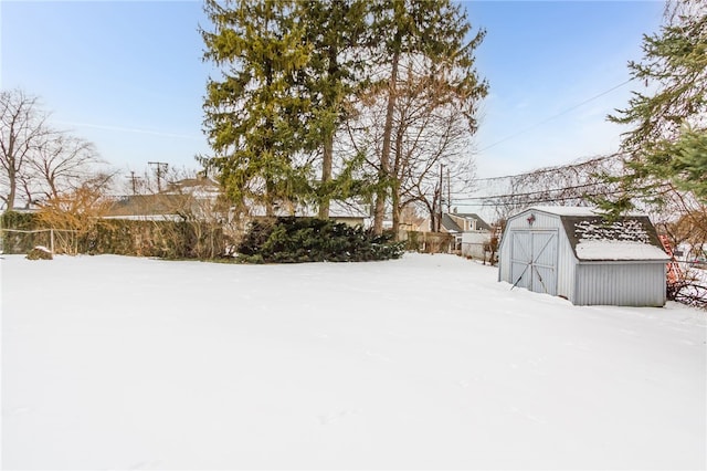 snowy yard with fence, an outdoor structure, and a shed