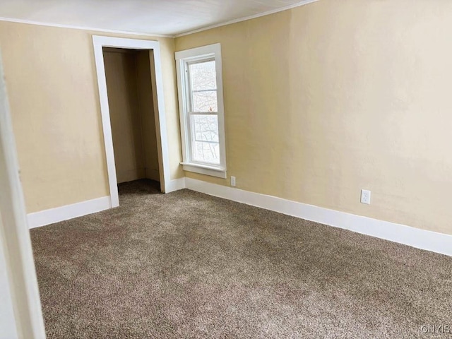 unfurnished bedroom featuring a closet, carpet flooring, crown molding, and baseboards