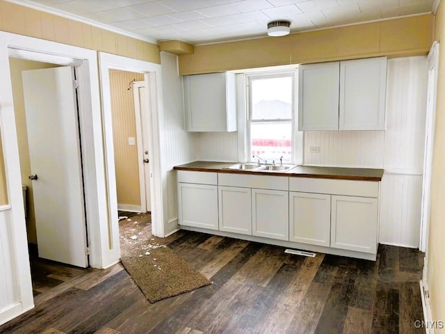 kitchen with dark wood finished floors, white cabinets, a sink, and visible vents