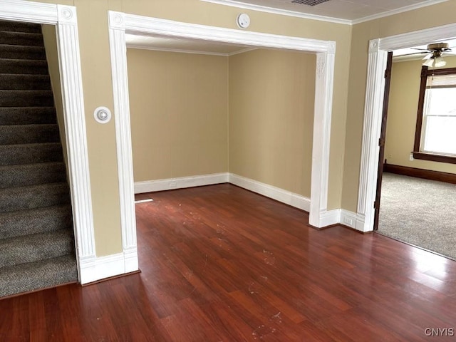 spare room with baseboards, a ceiling fan, ornamental molding, dark wood-style flooring, and stairs