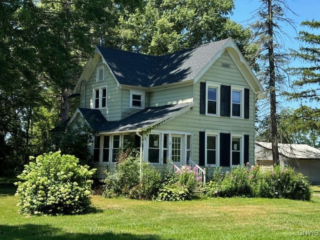 view of front of home featuring a front yard and roof with shingles