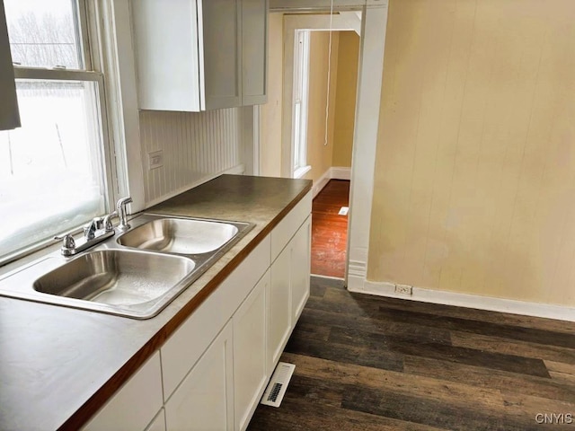 kitchen featuring dark wood-type flooring, white cabinetry, a sink, and visible vents