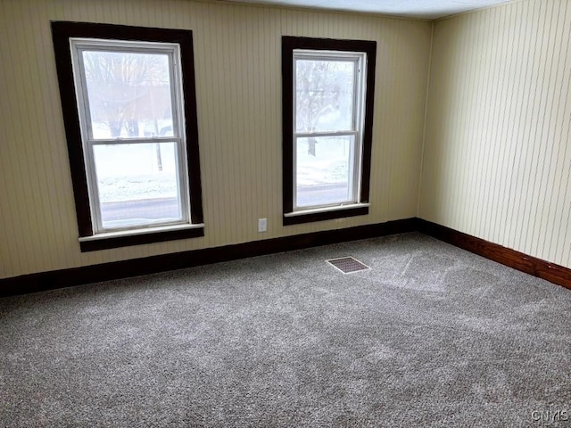 empty room with baseboards, visible vents, and carpet flooring