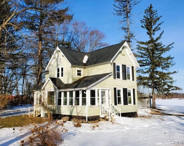 view of front of home with roof with shingles and a sunroom