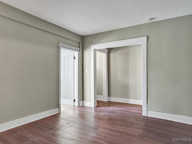 spare room with dark wood-style flooring and baseboards