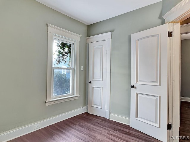 foyer featuring baseboards, wood finished floors, and a healthy amount of sunlight