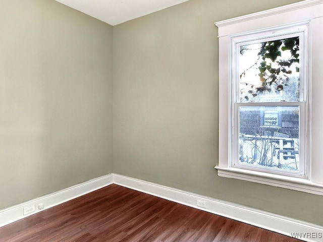 spare room featuring baseboards and wood finished floors