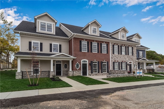 view of front of home featuring stone siding, brick siding, and a front yard