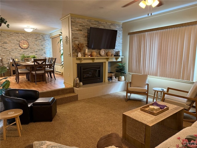 living room with ceiling fan, carpet flooring, a glass covered fireplace, and crown molding