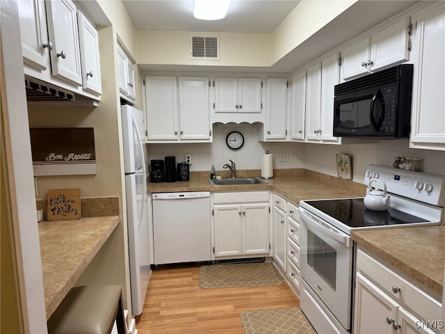 kitchen with white appliances, visible vents, white cabinets, and a sink