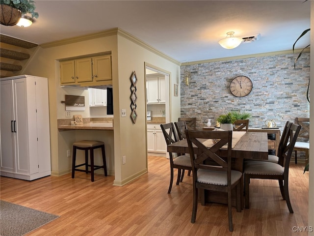 dining space with baseboards, light wood-type flooring, and crown molding