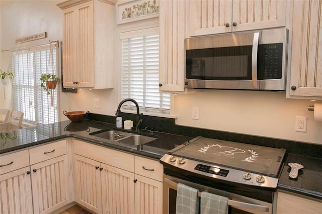 kitchen with dark countertops, a healthy amount of sunlight, stainless steel appliances, and a sink