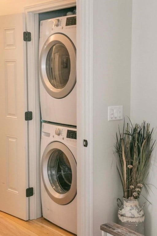 washroom with laundry area, light wood finished floors, and stacked washing maching and dryer