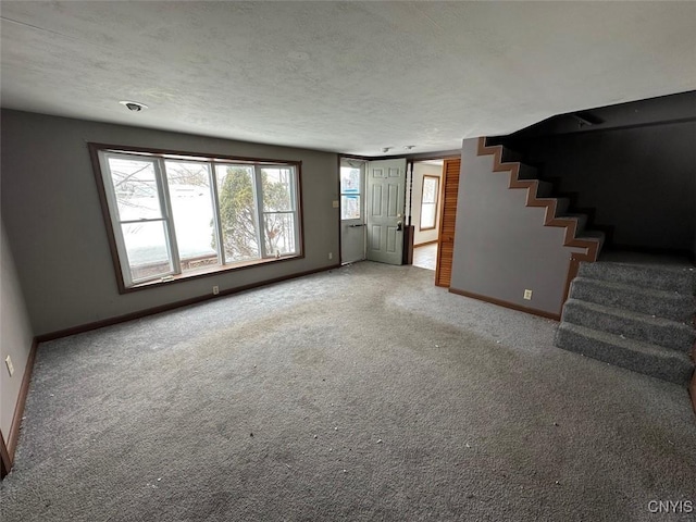 unfurnished living room featuring a textured ceiling, stairs, baseboards, and carpet flooring