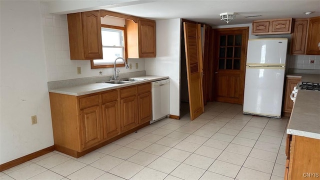 kitchen featuring light countertops, white appliances, a sink, and brown cabinets