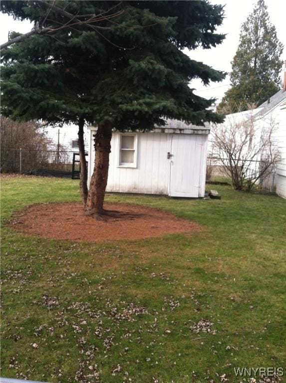 view of yard with a storage shed, fence, and an outbuilding