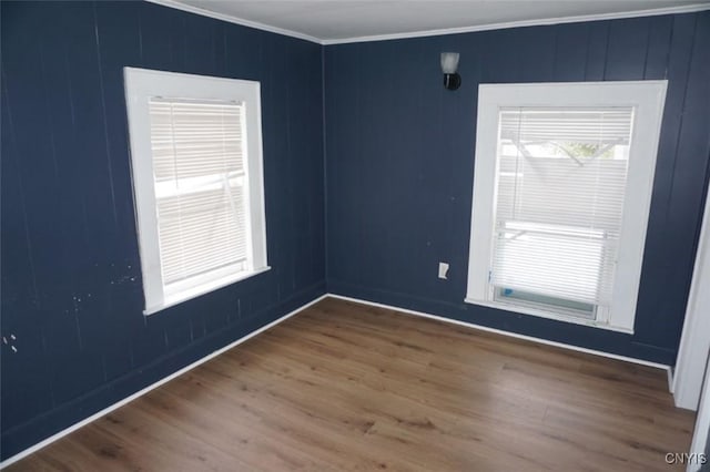 spare room with ornamental molding and wood finished floors