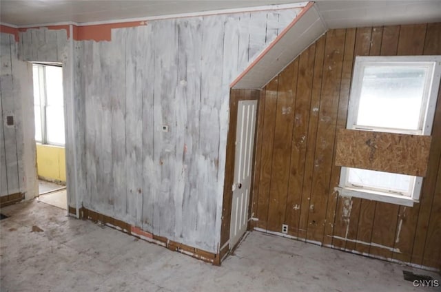 bonus room with vaulted ceiling and wood walls