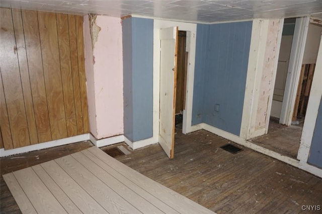 interior space featuring dark wood-style flooring, visible vents, and wood walls