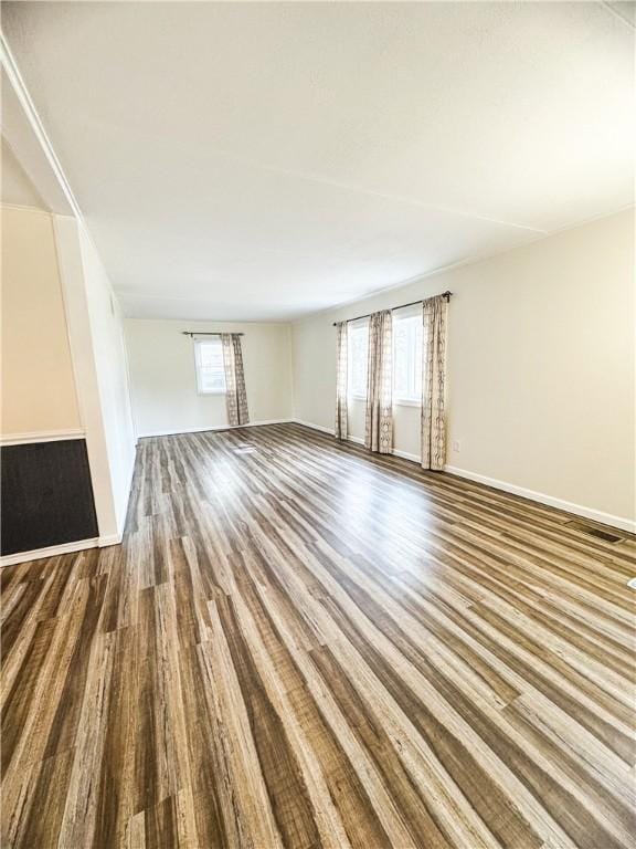 unfurnished living room featuring baseboards and wood finished floors