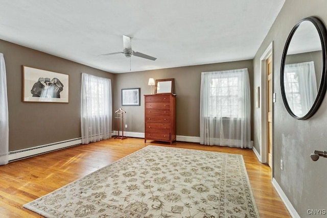 foyer with a baseboard heating unit, baseboards, a ceiling fan, and light wood-style floors