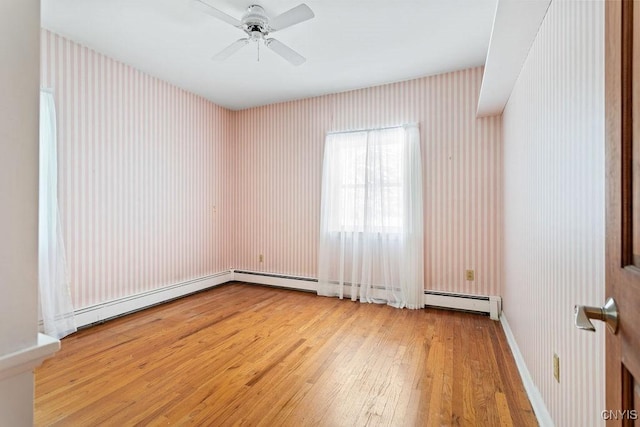 spare room featuring baseboards, baseboard heating, a ceiling fan, and light wood-style floors