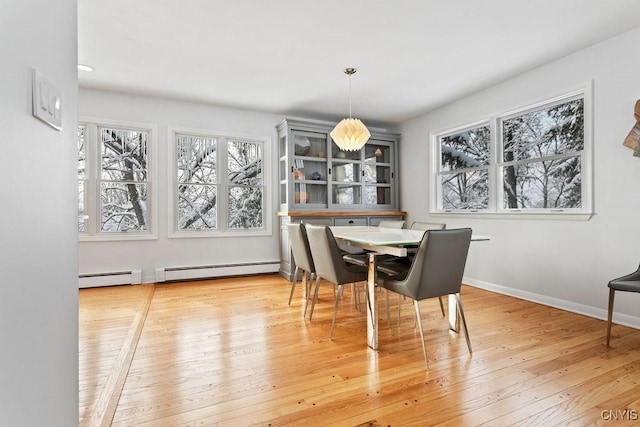 dining room featuring a baseboard heating unit, wood-type flooring, and baseboards