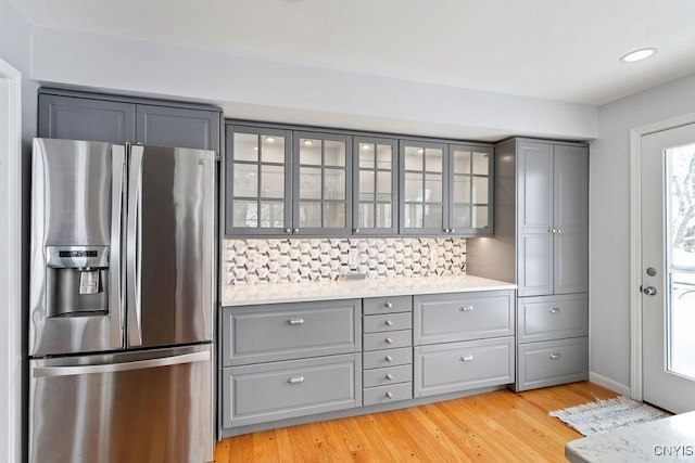 kitchen with light countertops, stainless steel fridge, and glass insert cabinets