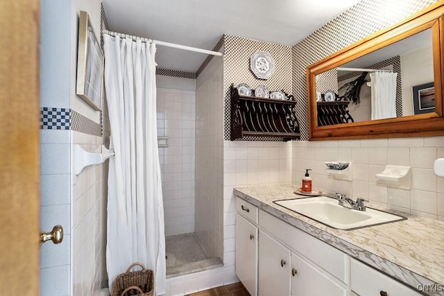 full bath with a stall shower, vanity, and tile walls